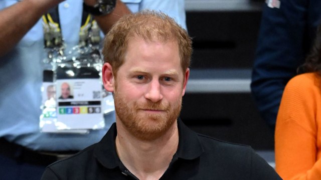 Prince Harry in a black shirt with his hand over his heart