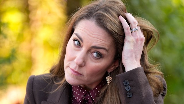 Kate Middleton pushing her hair back with four rings on her left hand