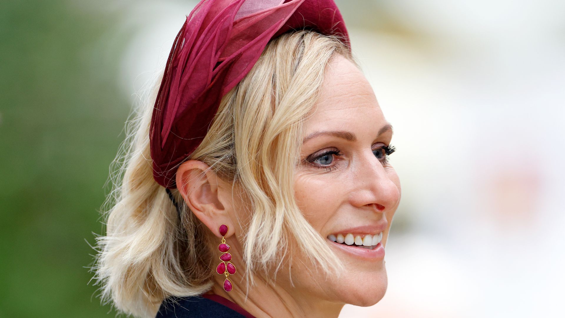 Zara Tindall close up wearing raspberry coloured headband