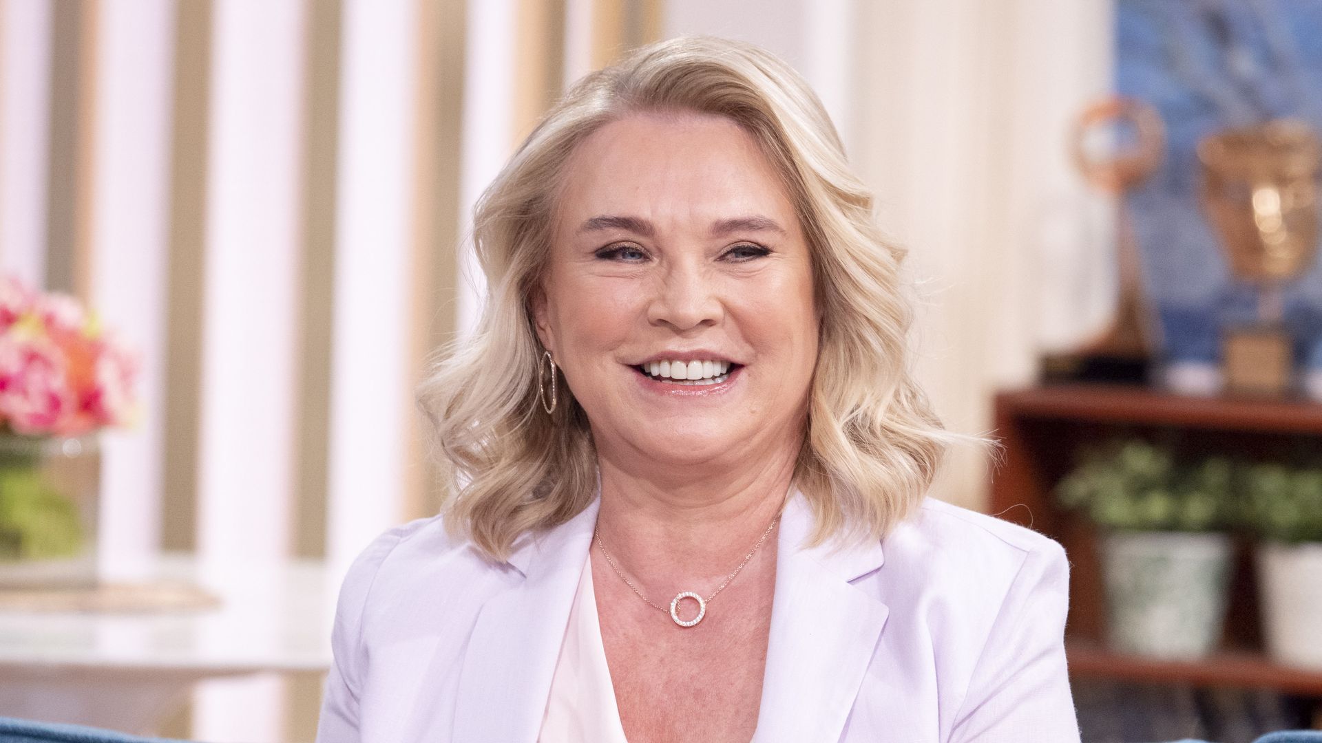 blonde woman sitting on blue sofa in tv studio