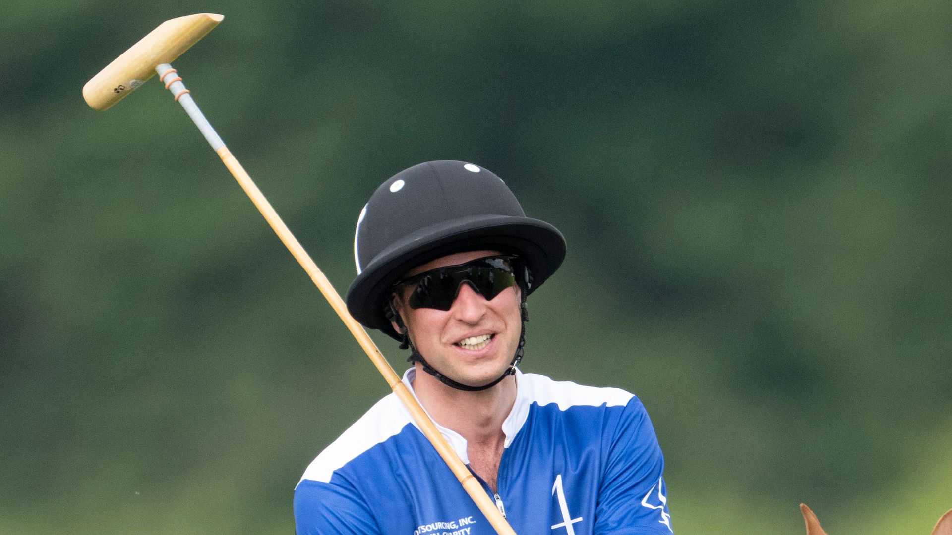 Prince William smiling while in polo uniform and holding a mallet
