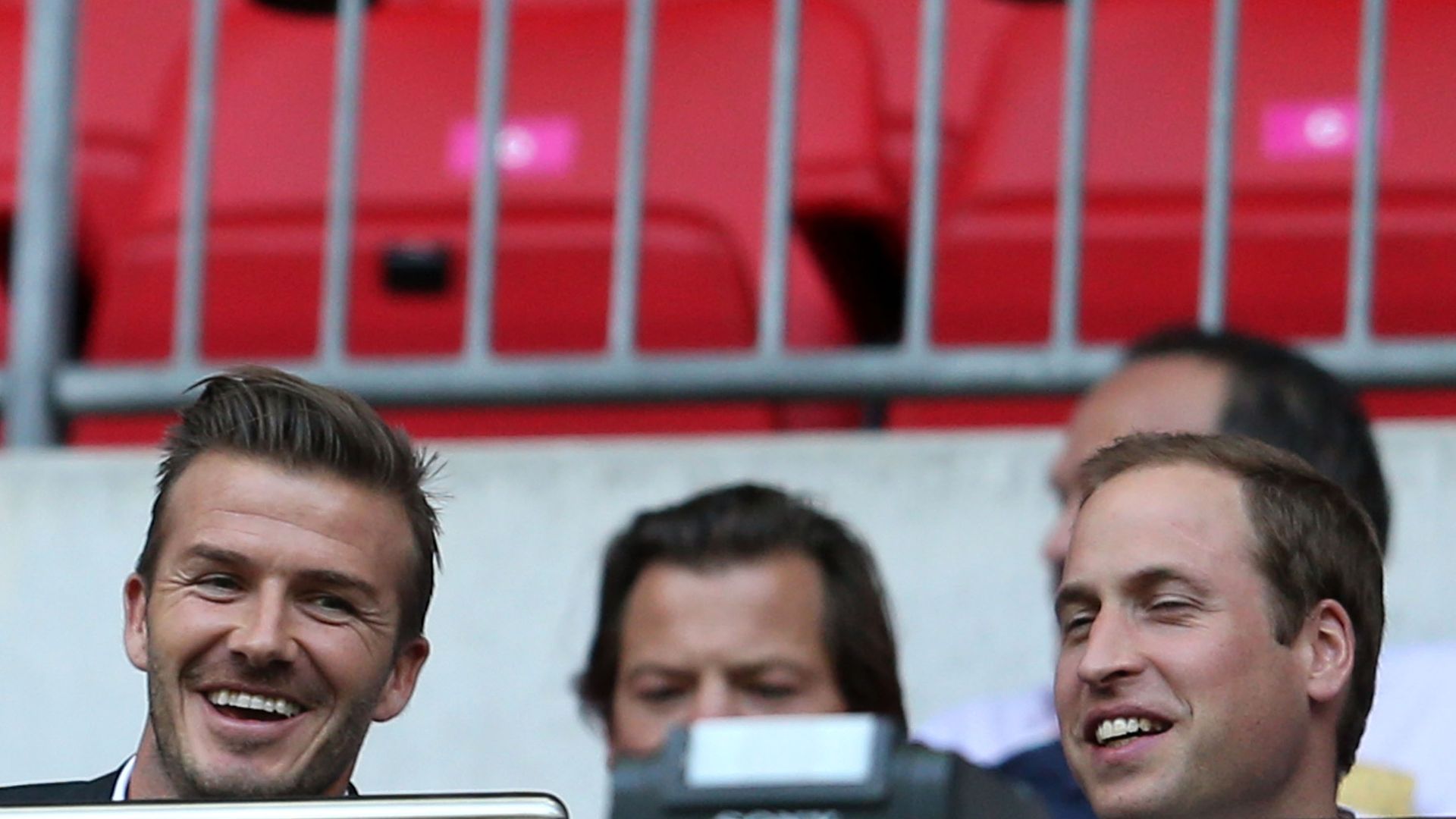 The heads of David Beckham and Prince William laughing together