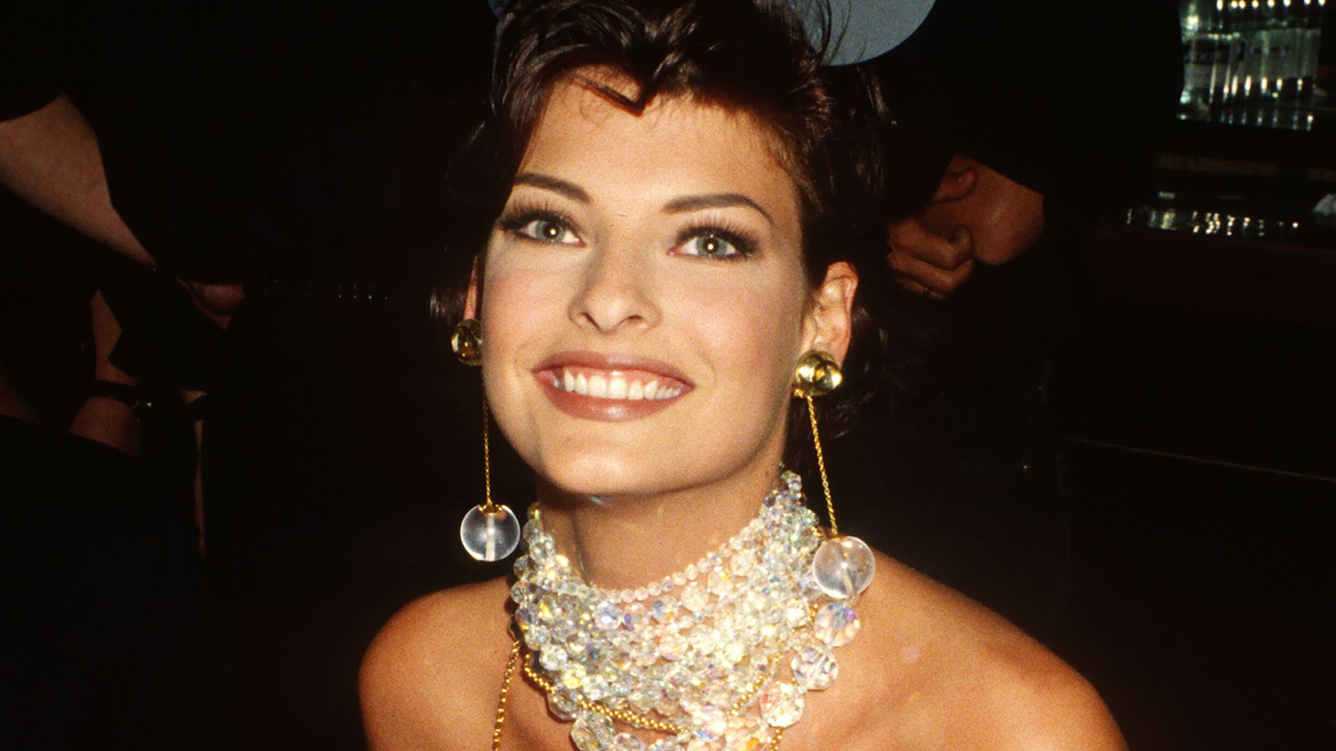 Linda Evangelista smiling at a Paris Fashion Week event in the 90s