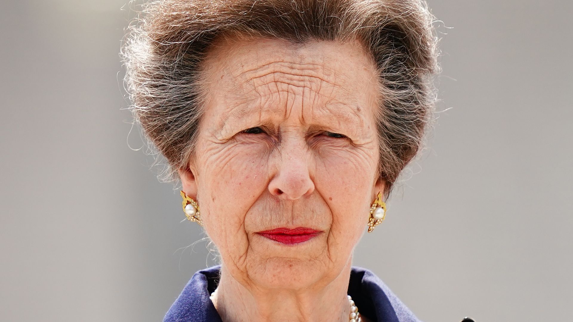 Princess Anne looking sombre in blue coat and pearls