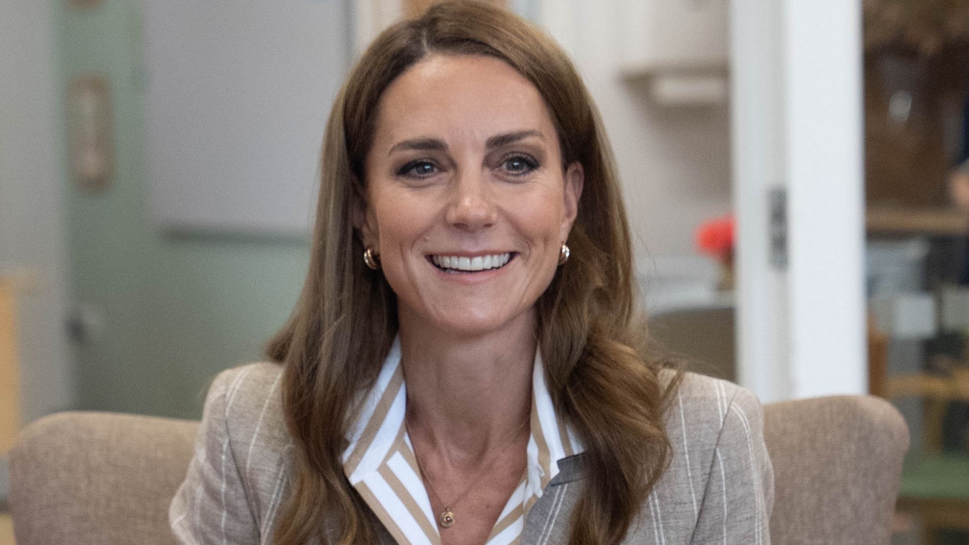 Princess of Wales holding cup of tea and wearing blazer and striped shirt