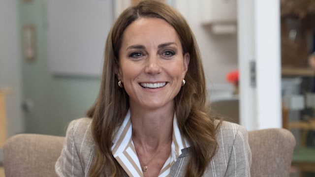 Princess of Wales holding cup of tea and wearing blazer and striped shirt