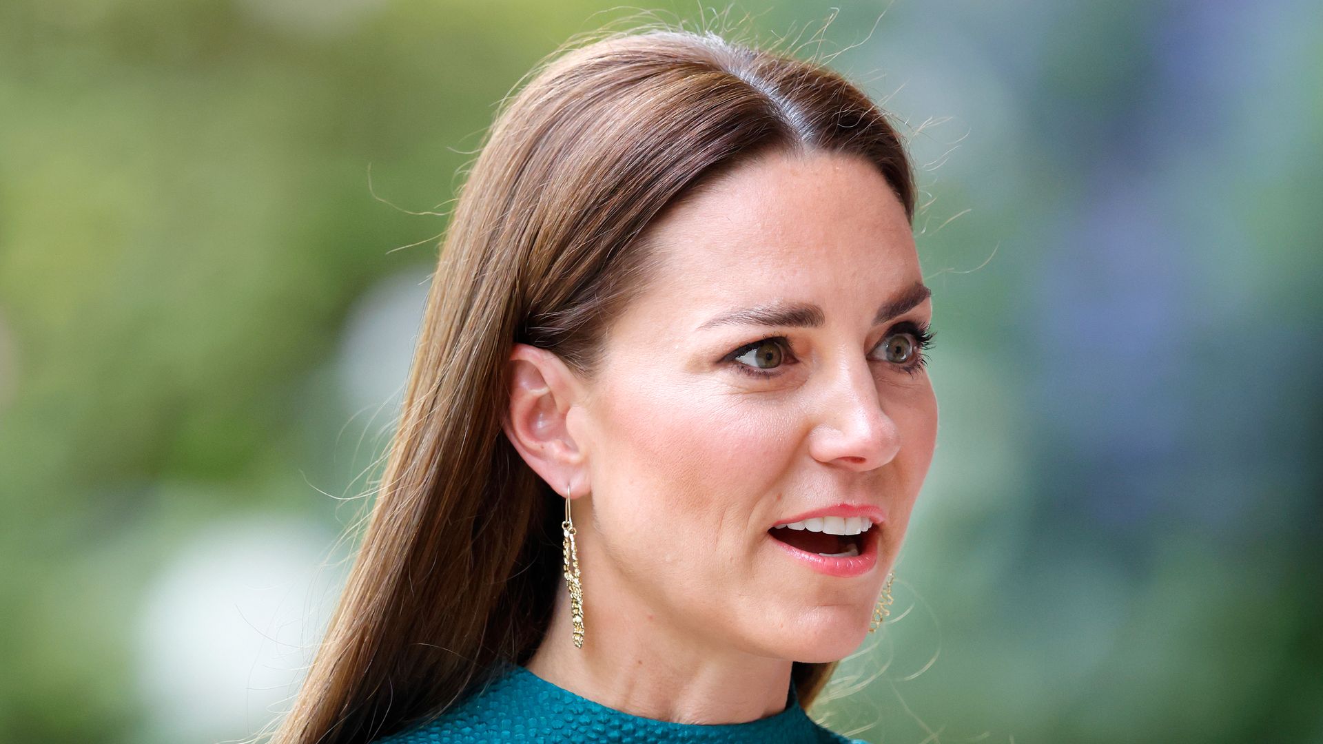 Catherine in teal dress shoulders up looking shocked