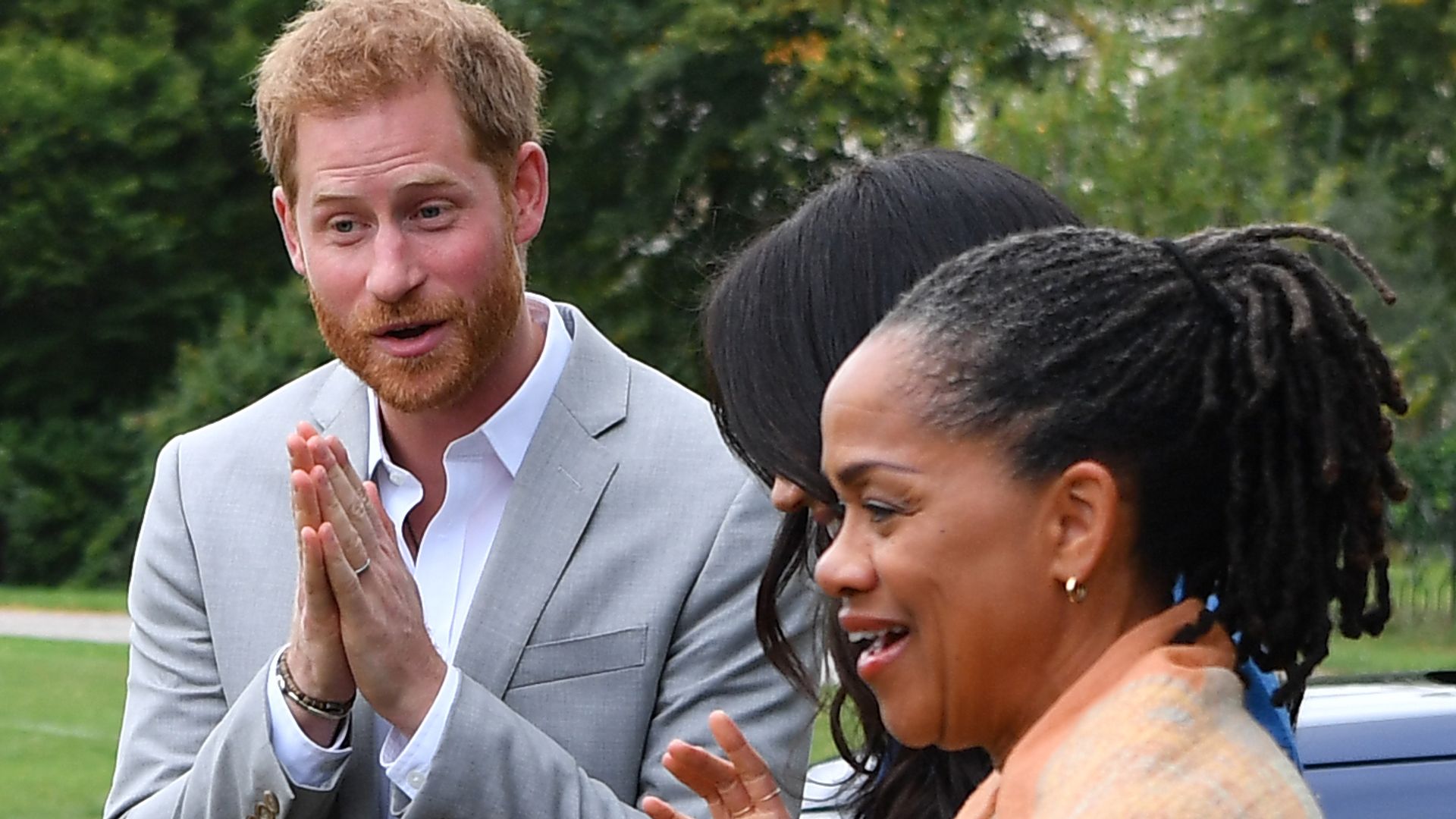 Prince Harry, Meghan Markle and her mother Doria Ragland standing outside smiling and talking