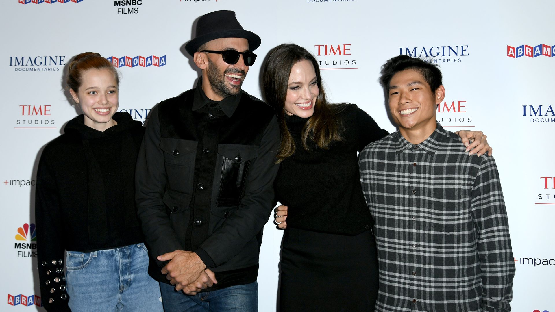Angelina with Shiloh and Pax and her friend, street artist JR, smiling at each other on a red carpet