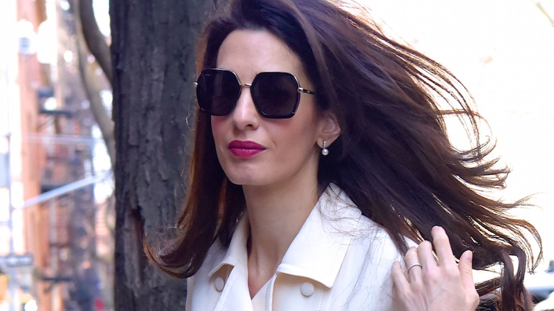 Amal Clooney flipping her hair in a white skirt