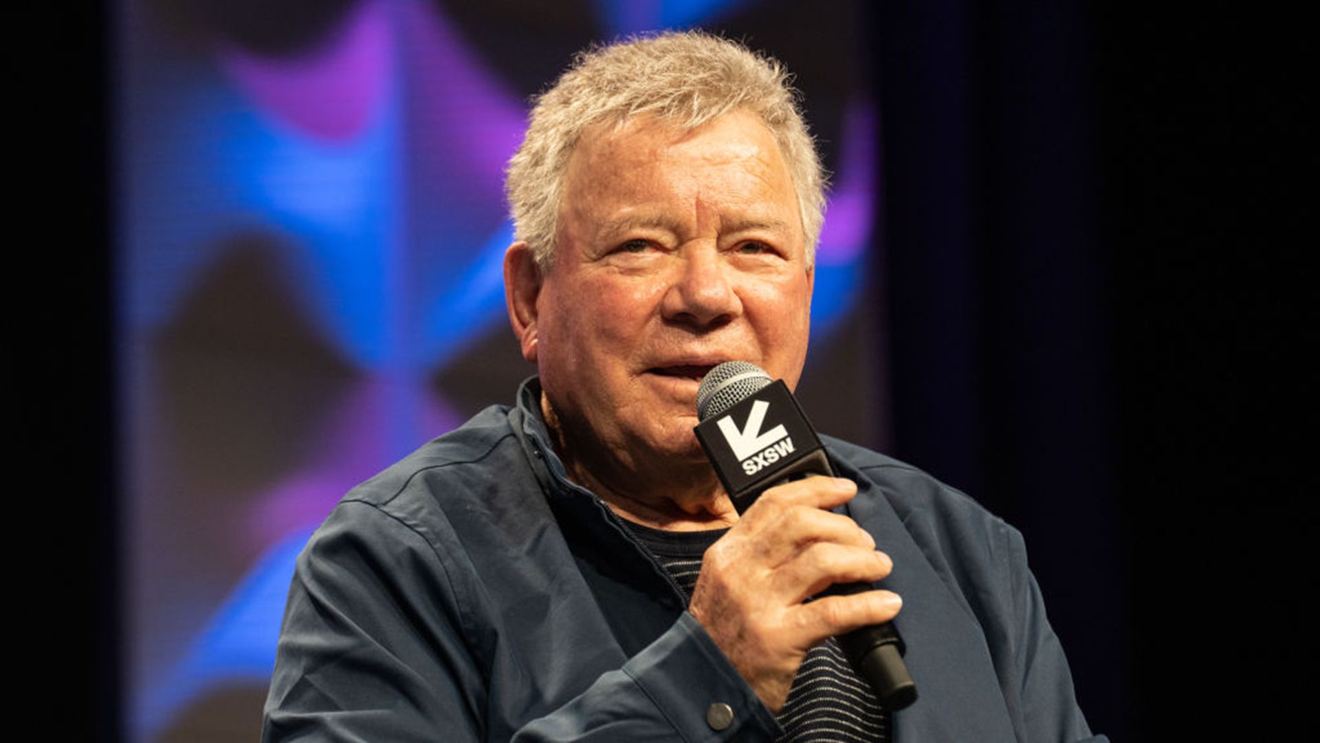 William Shatner speaking into a microphone. 