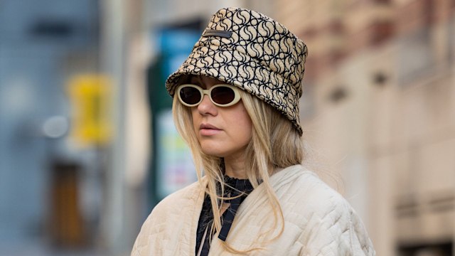 Joicy Muniz wears black bag with heart shape bag, bucket hat, belted jacket, brown pants, net shoes, sunglasses during Paris Fashion Week - Womenswear Fall Winter 2023 2024 : Day Three on March 01, 2023 in Paris, France