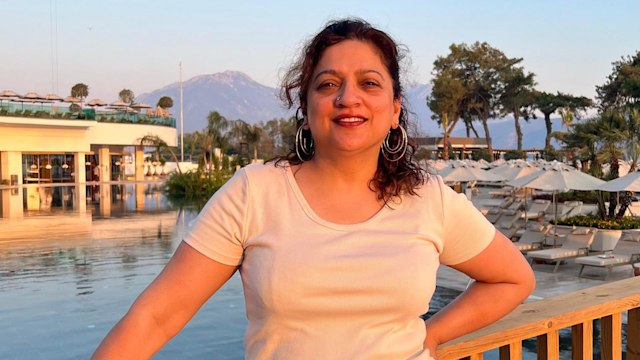 woman in a white top posing in front of a pool