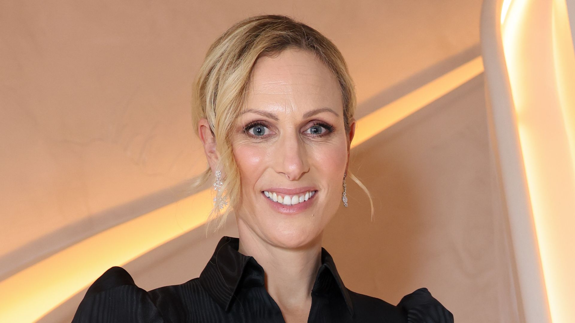 Zara Tindall standing on a flight of stairs in a black mini dress