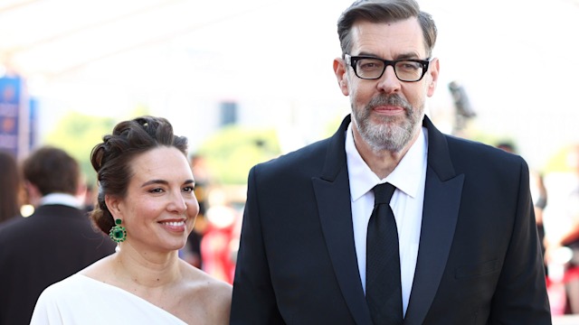 Richard Osman holding hands with his wife Ingrid Oliver in a white dress