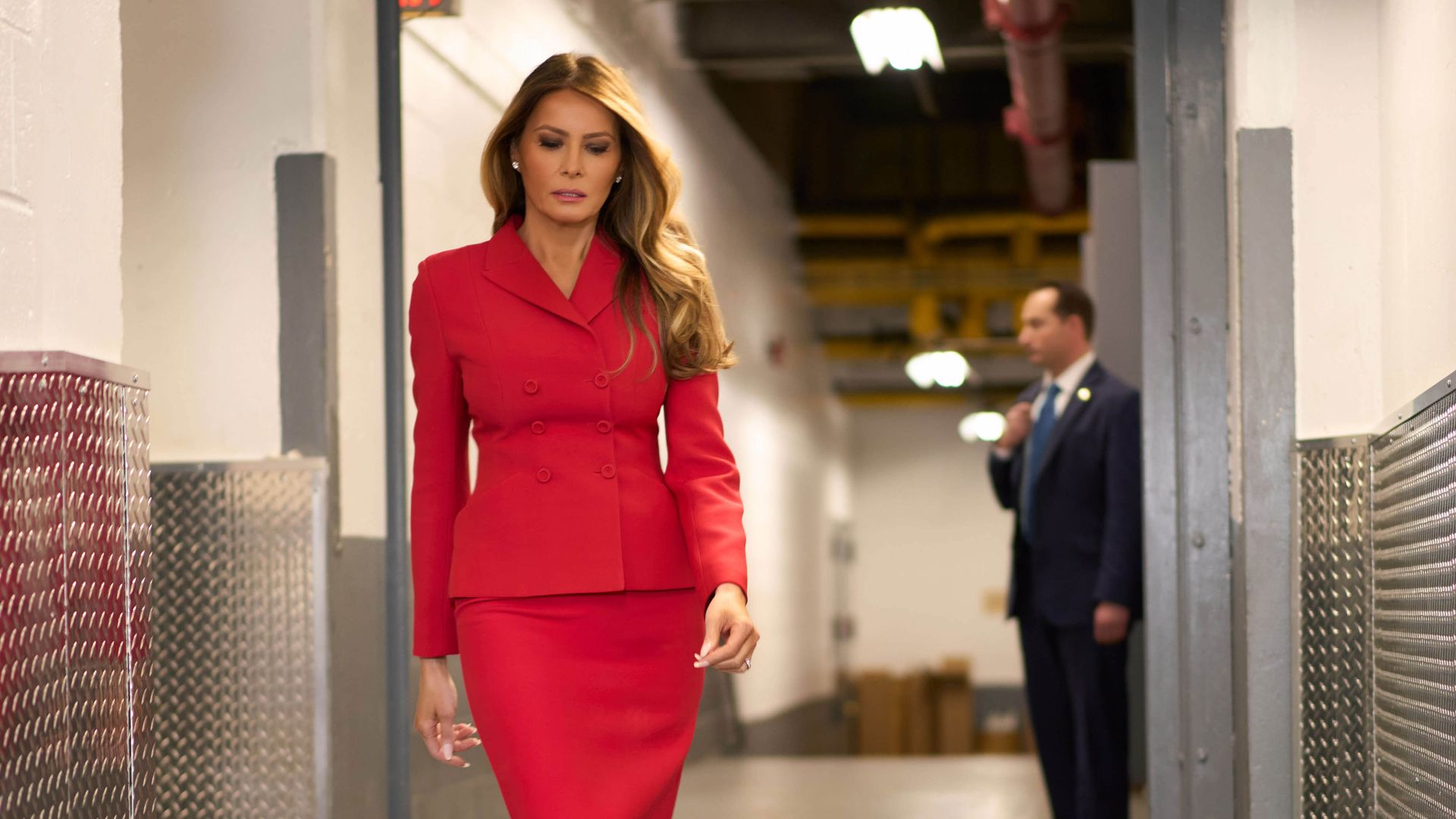 Melania Trump walking whilst wearing a red suit and matching heels