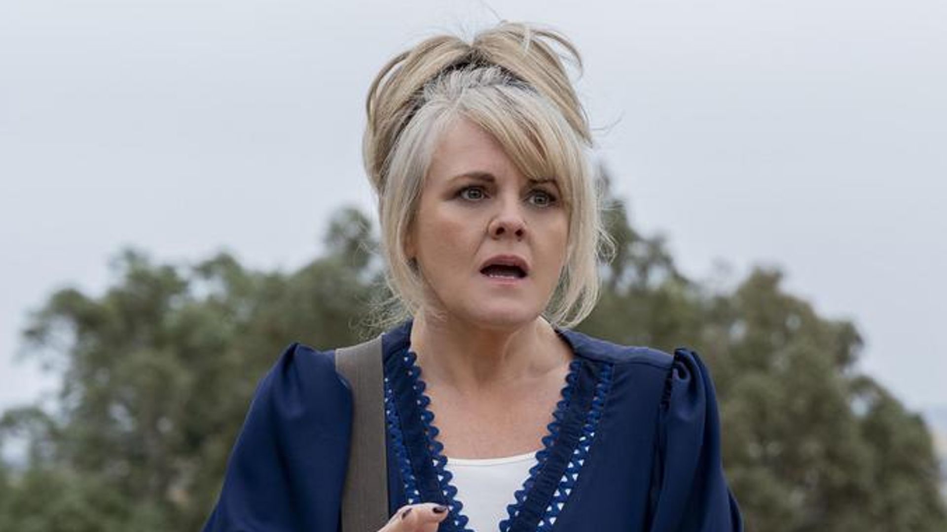 blonde woman looking shocked standing on roof top. Sally Lindsay in The Madame Blanc Mysteries