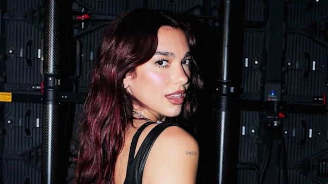 Dua Lipa poses in a black body suit while on tour