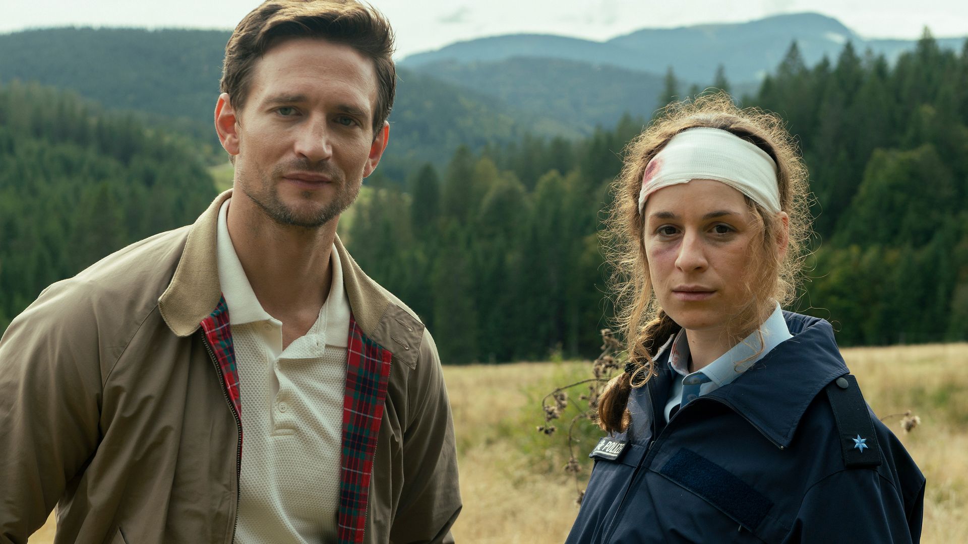 man and woman standing in filed in front of mountains