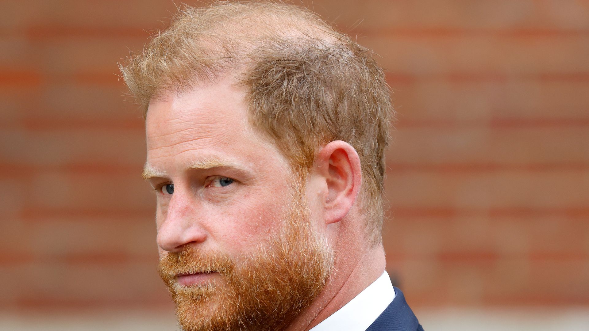 Prince Harry with a stern expression in a blue suit