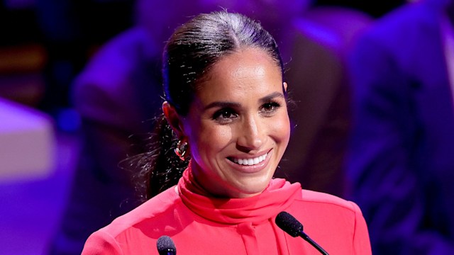 Meghan Markle smiling in a red outfit