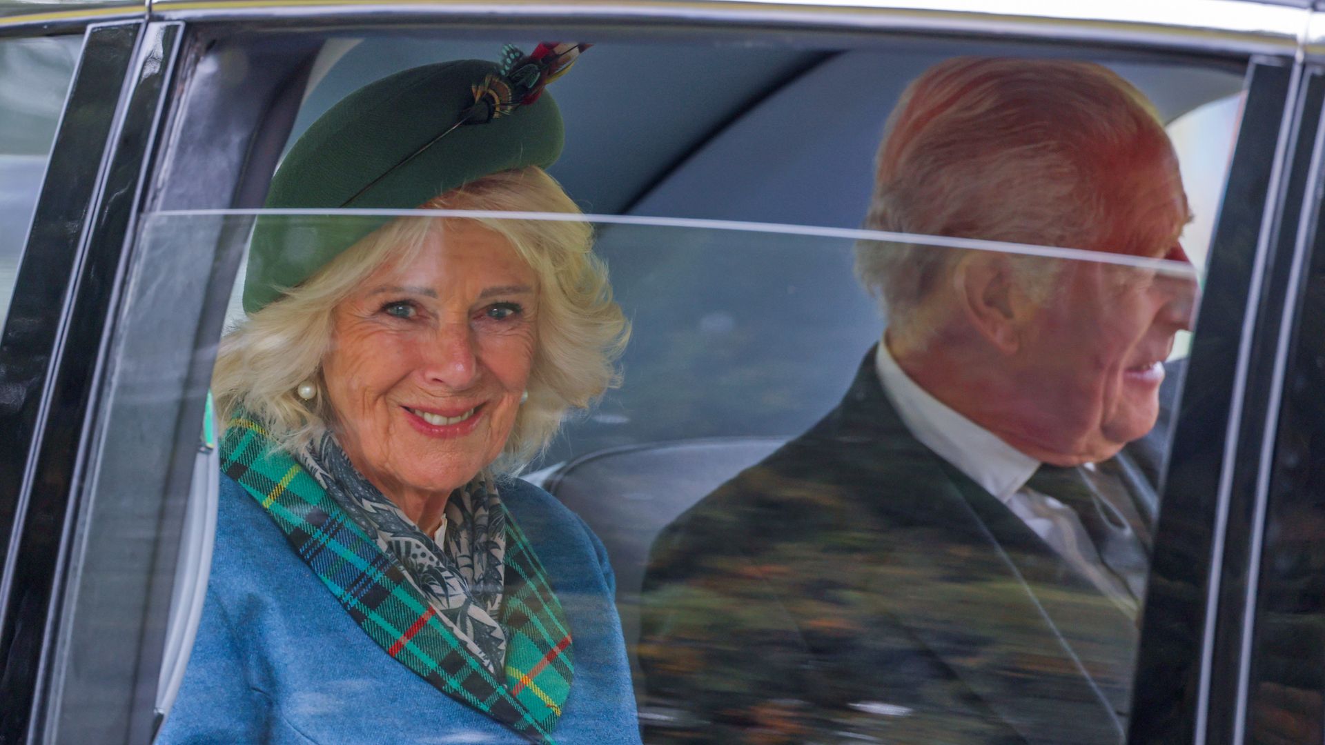 Queen Camilla and King Charles looking out of a car window