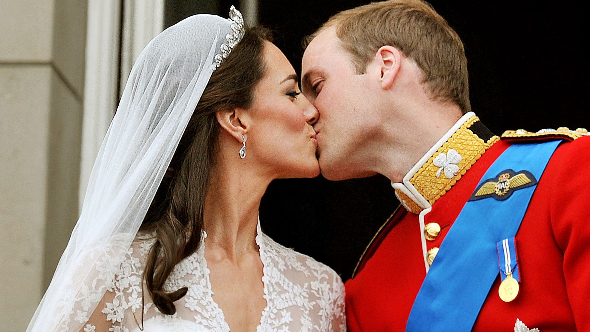 Prince William in a red military uniform kissing his new bride Kate Middleton