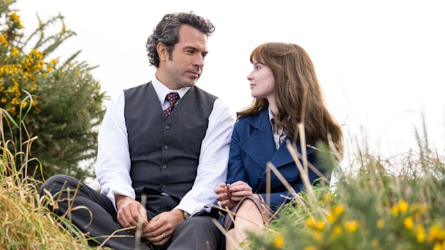 Man and woman sitting on grassy hill
