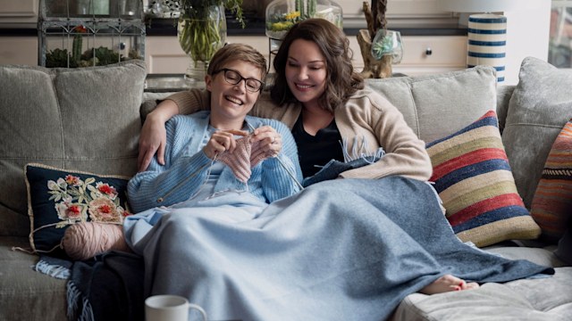 Sarah Chalke as Kate, Katherine Heigl as Tully in season two episode 16 of Firefly Lane. They are cuddled up on the sofa. 