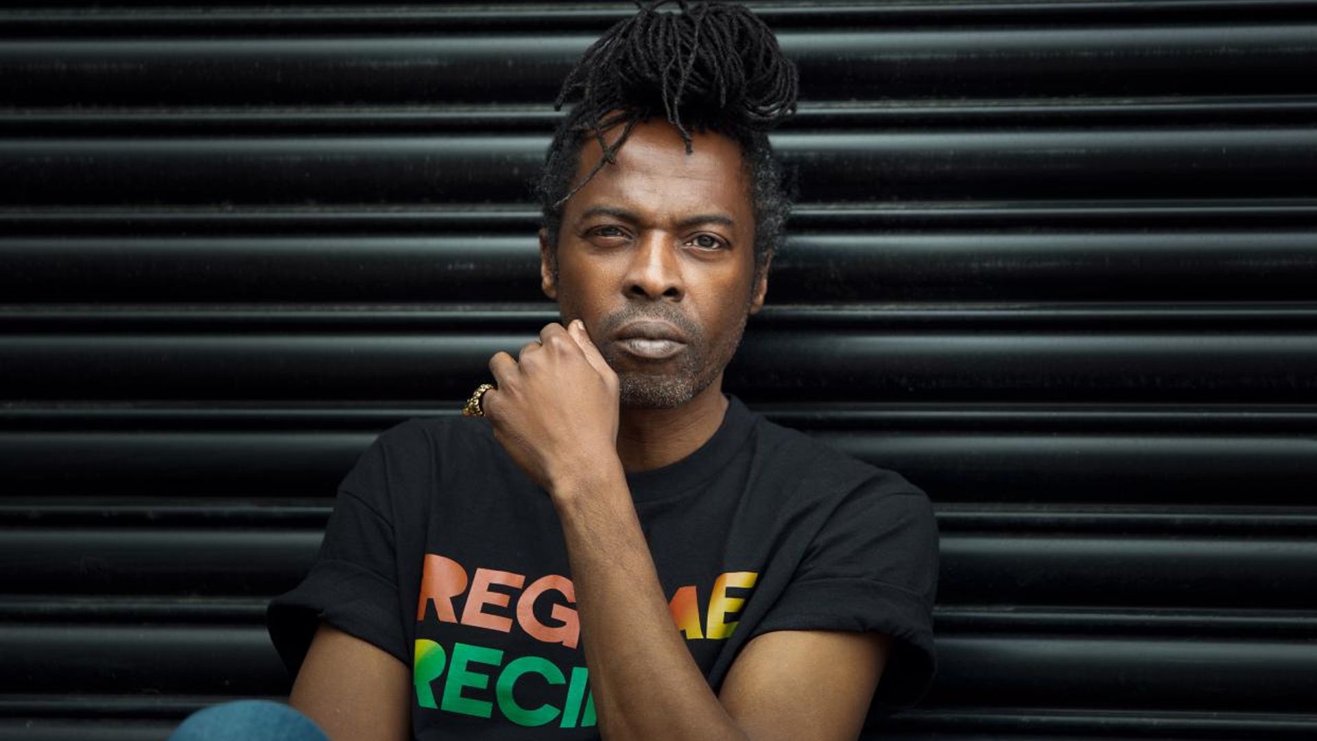 man sitting against black wall