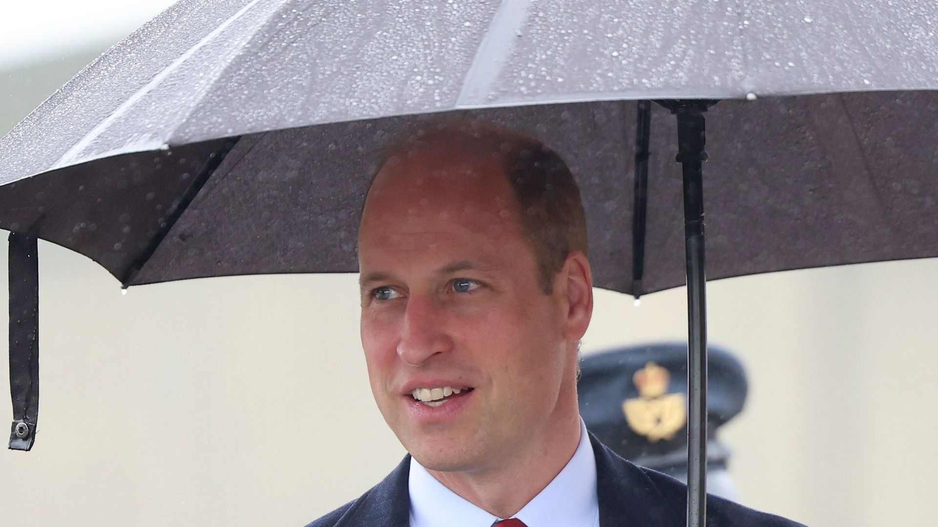 prince william in blue suit holding umbrella 