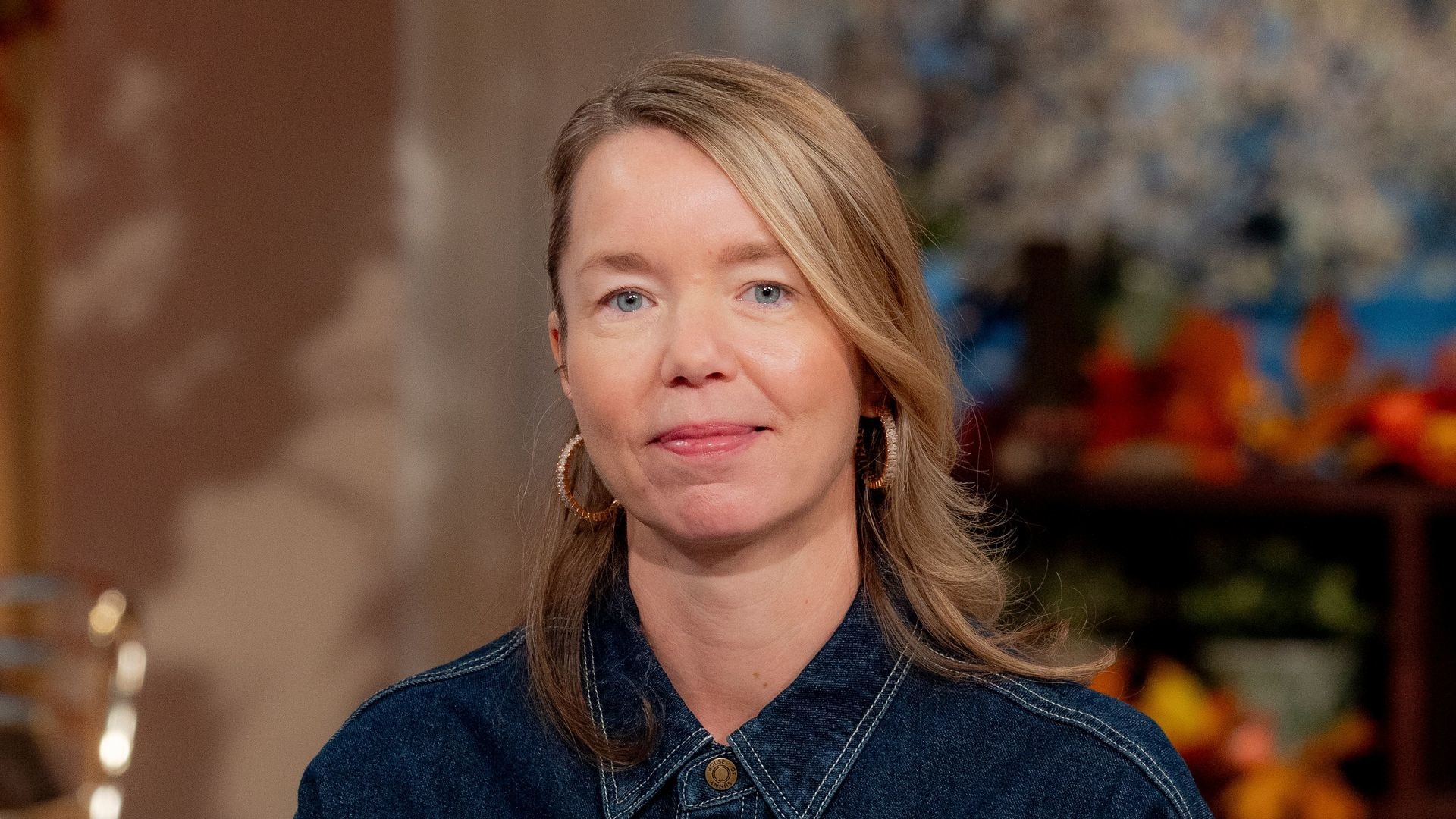 blonde woman in denim dress on blue sofa in tv studio