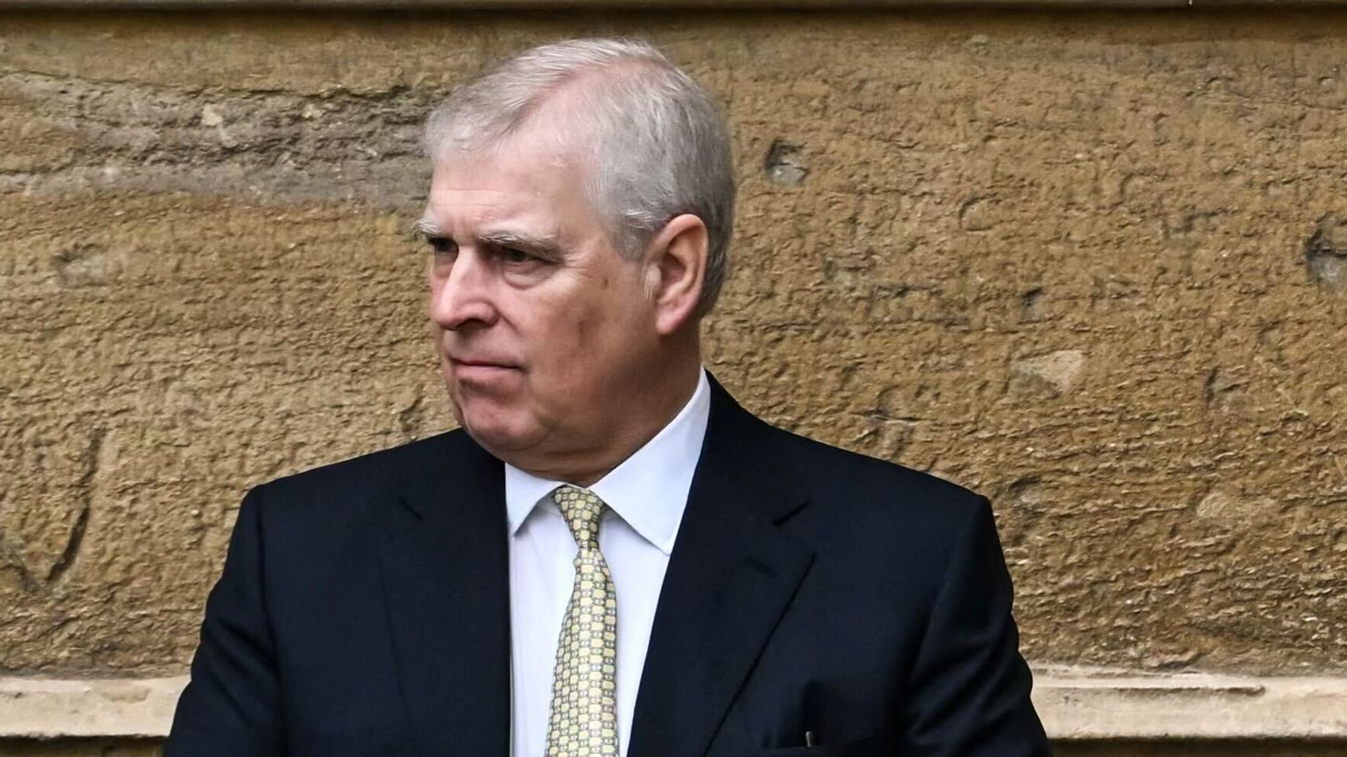 Prince Andrew standing by a wall