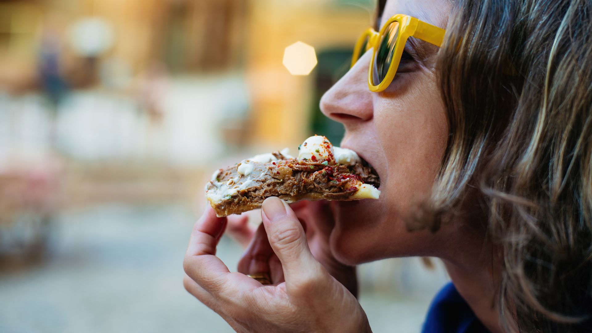 woman eating slice of pizza 