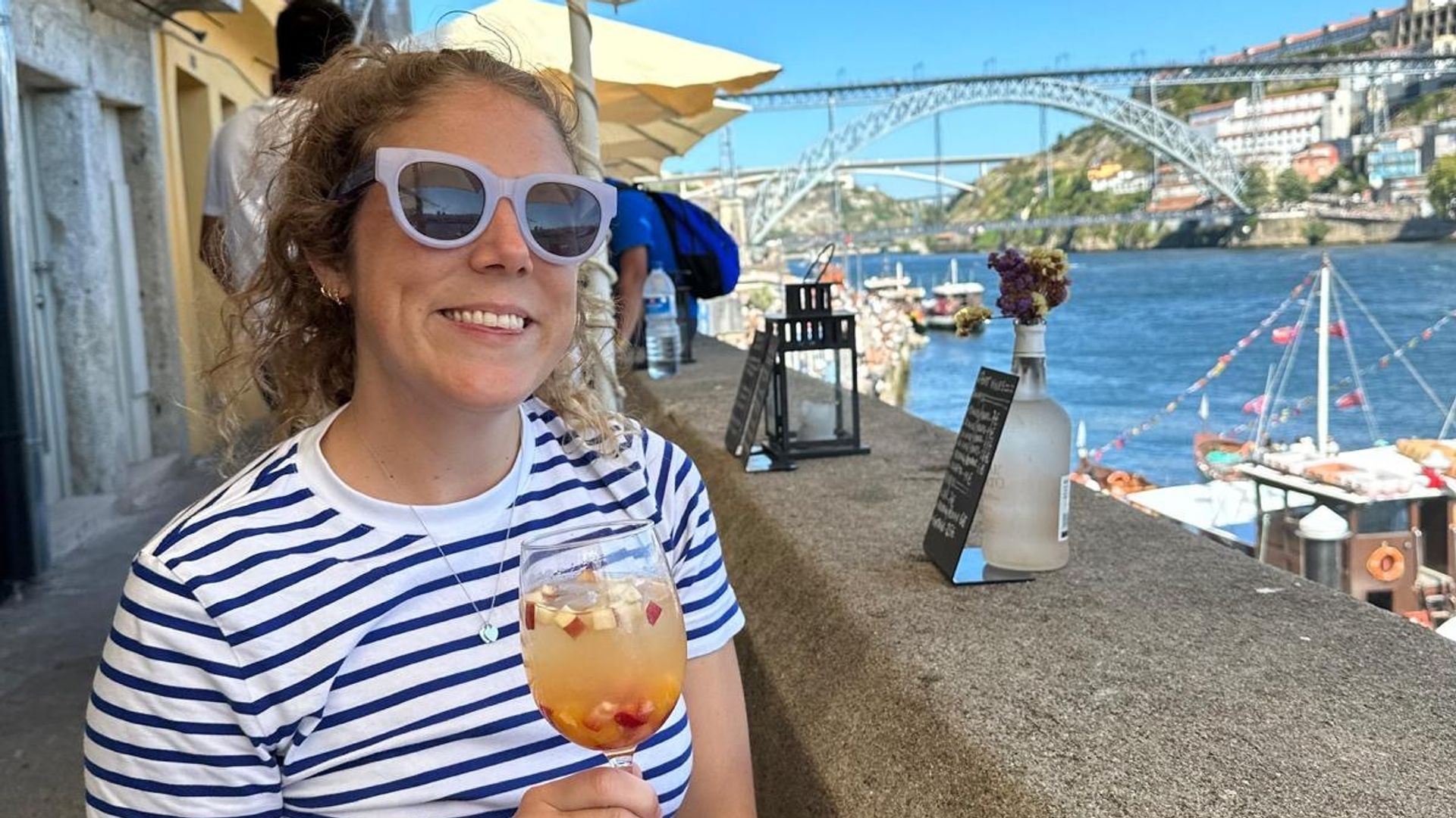 Mel with a drink in stripey top and sunglasses