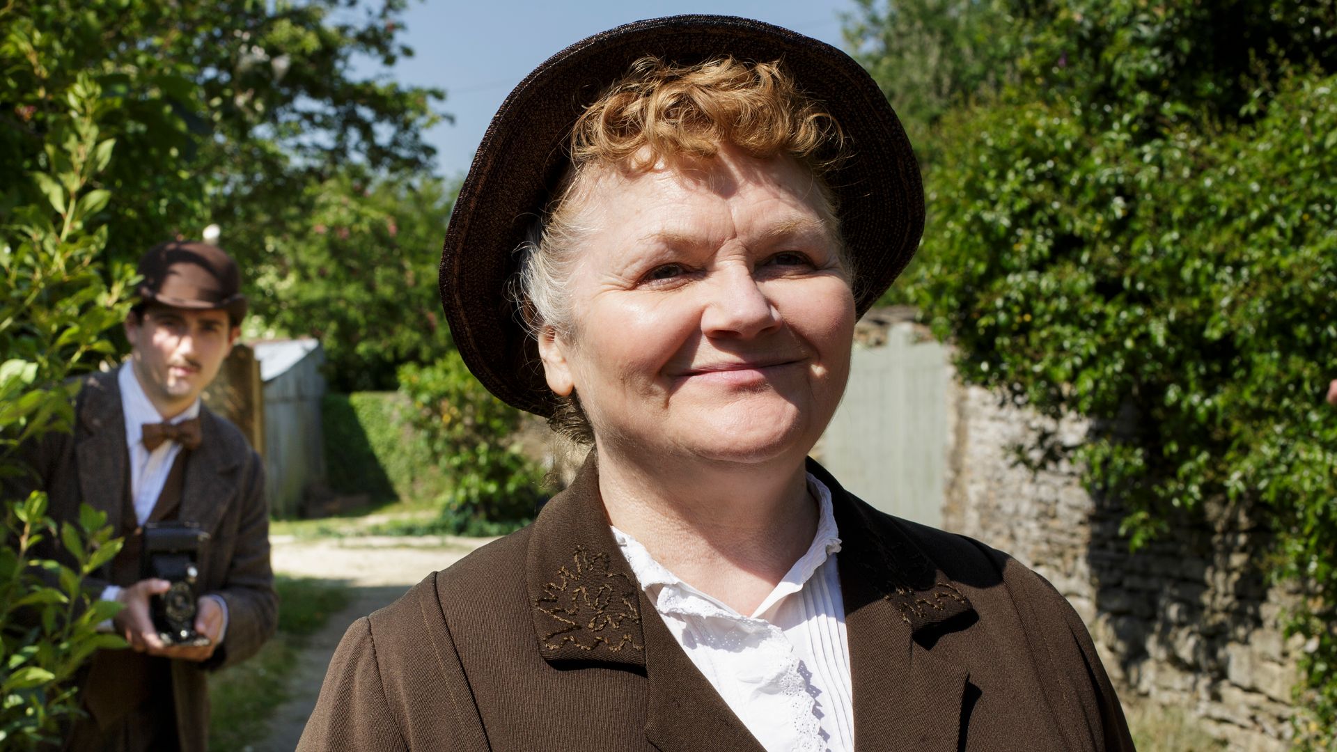 woman standing in path way in hat and coat