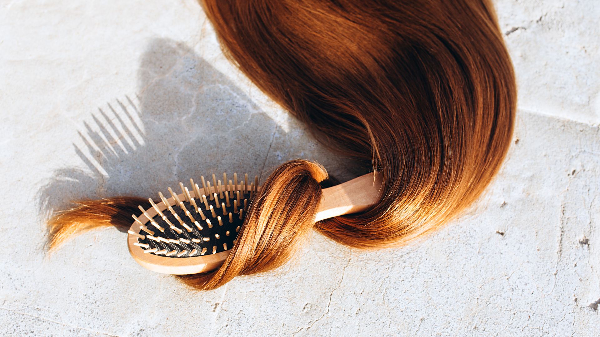 Shiny Long hair with a comb lies on a stone on a sunny day..