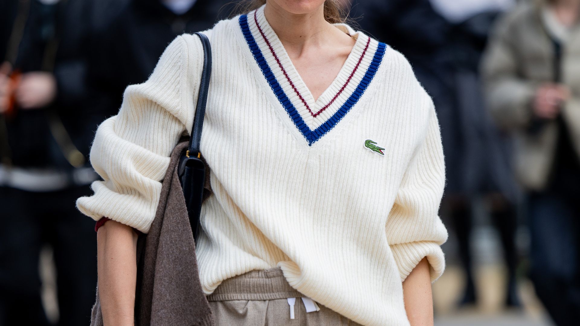 Monica de La Villardiere wears v neck knit, beige pants, black bag, sunglasses outside Lacoste during the Womenswear Fall/Winter 2024/2025 as part of  Paris Fashion Week