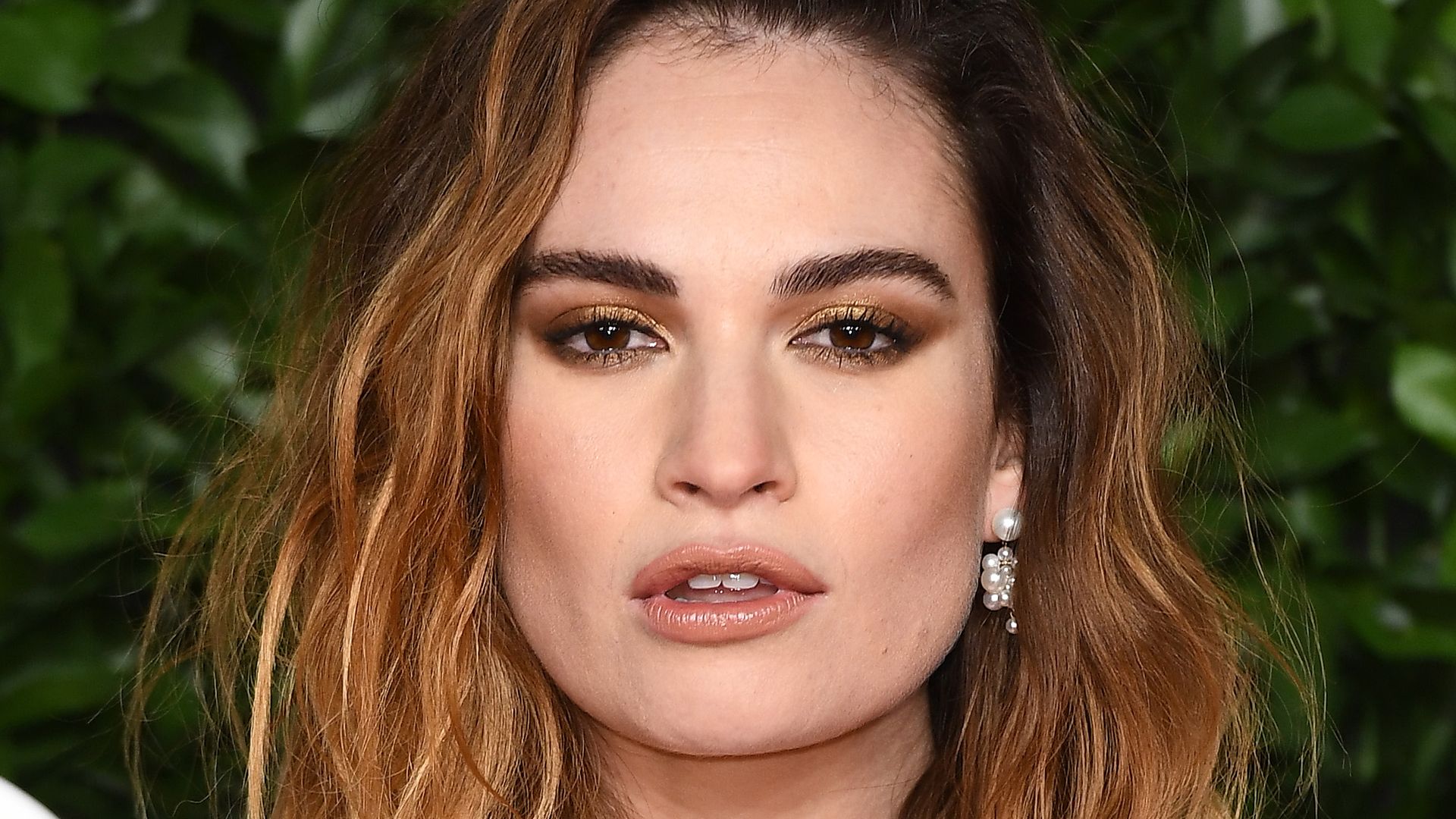 Lily James with beachy brunette waves and bronze eyeshadow at The Fashion Awards 2019