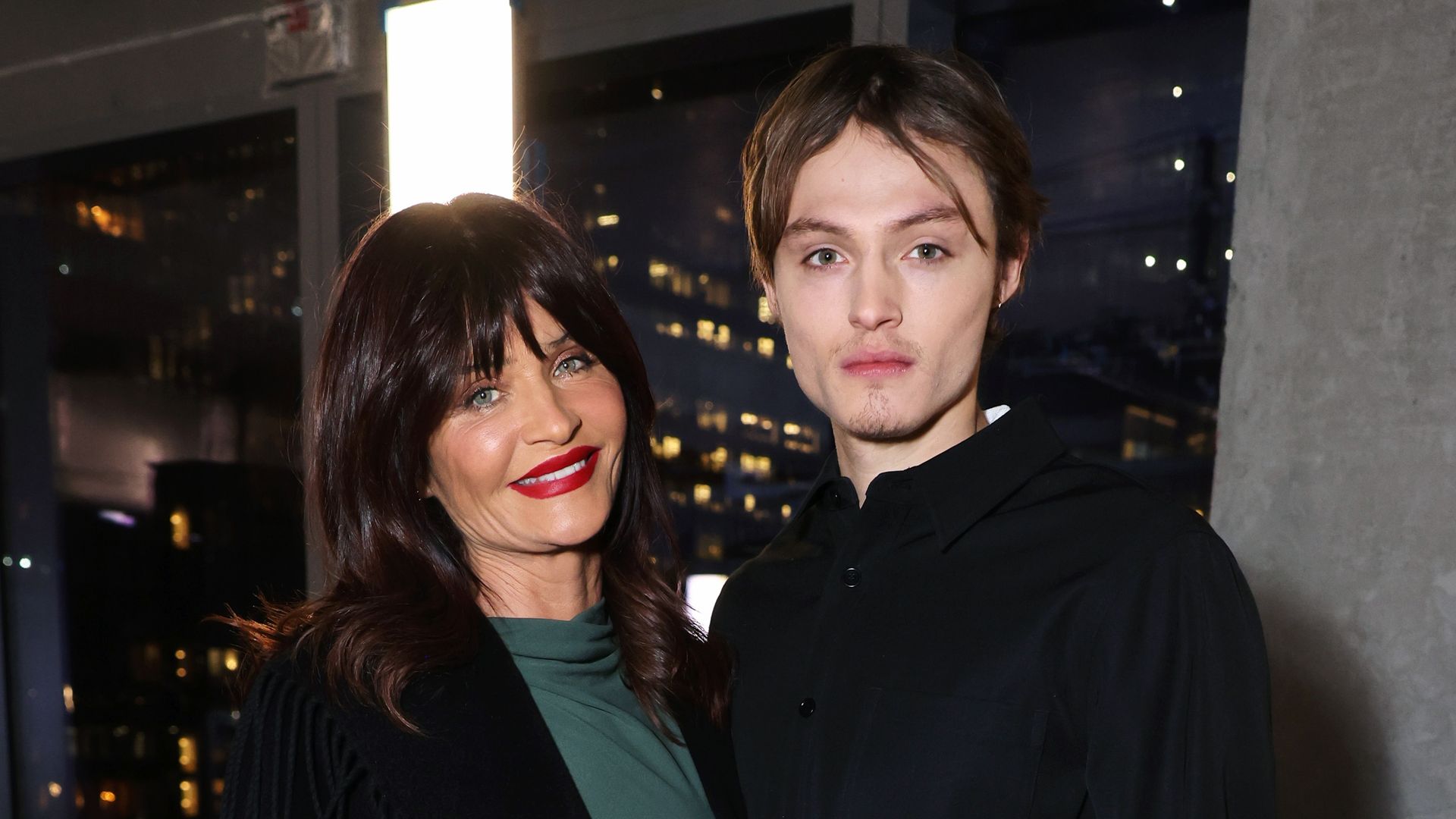 Helena Christensen in green dress and black coat and Mingus Lucien Reedus in black shirt at the SIMKHAI show