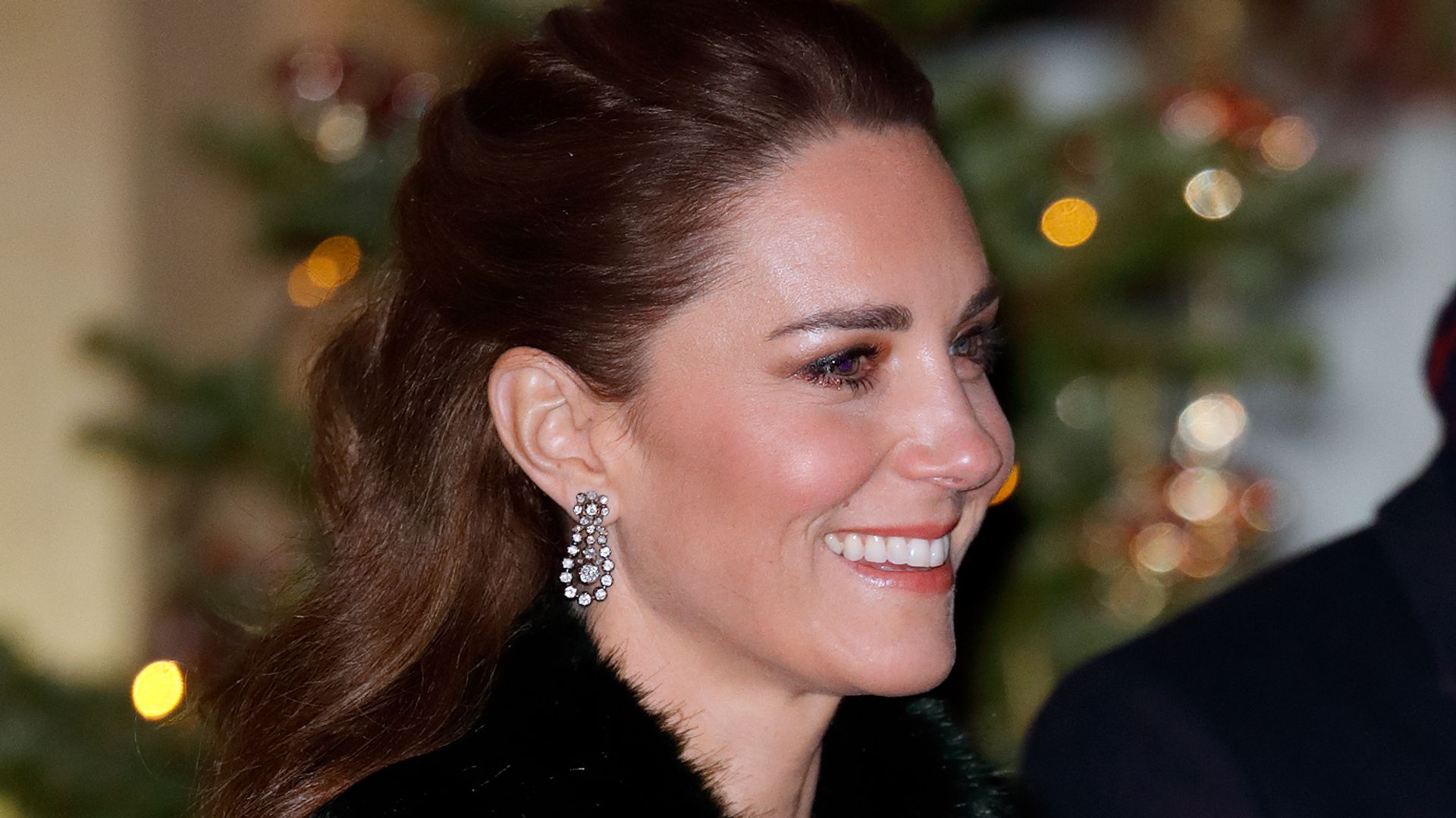 Kate Middleton in a green fluffy coat in front of a Christmas tree