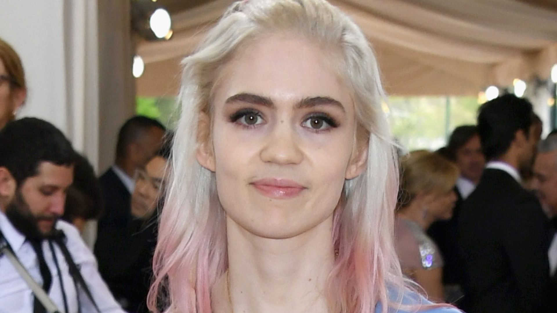 Singer Grimes in a blue silky dress with blonde and pink hair