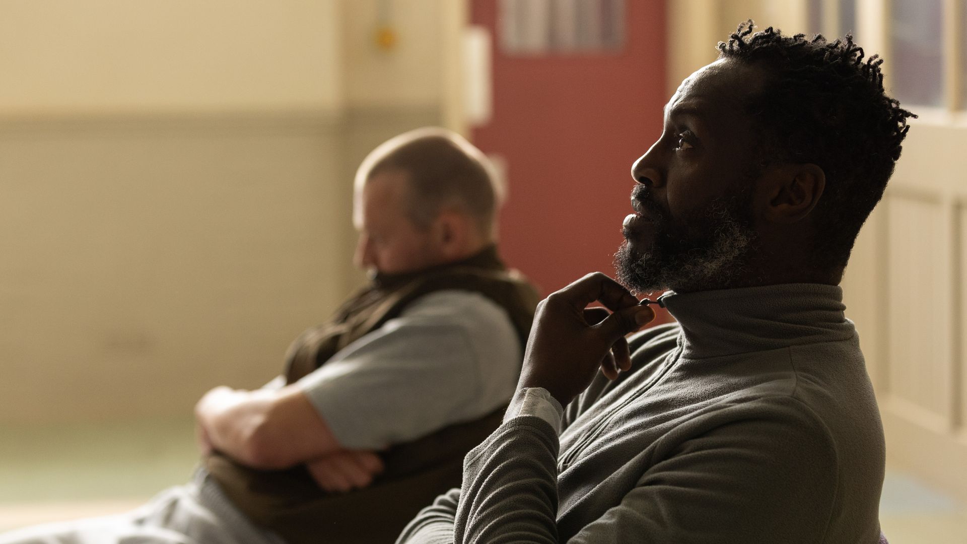 Charlie Rix and Sule Rimi sitting in chairs in a prison in a scene from Waiting for the Out