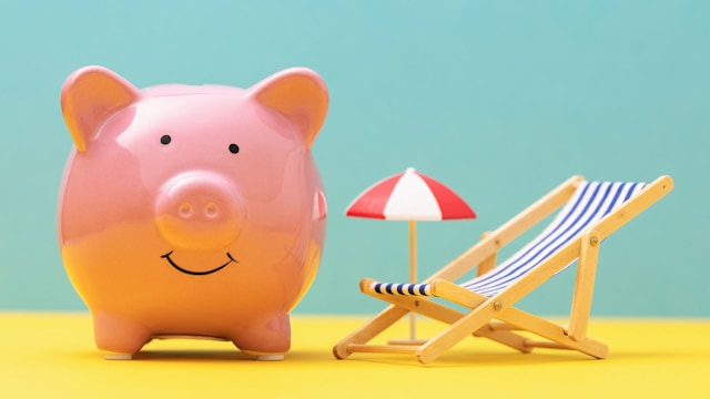 Pink piggy bank, toy deck chair and umbrella on colored background, vacation money saving concept.