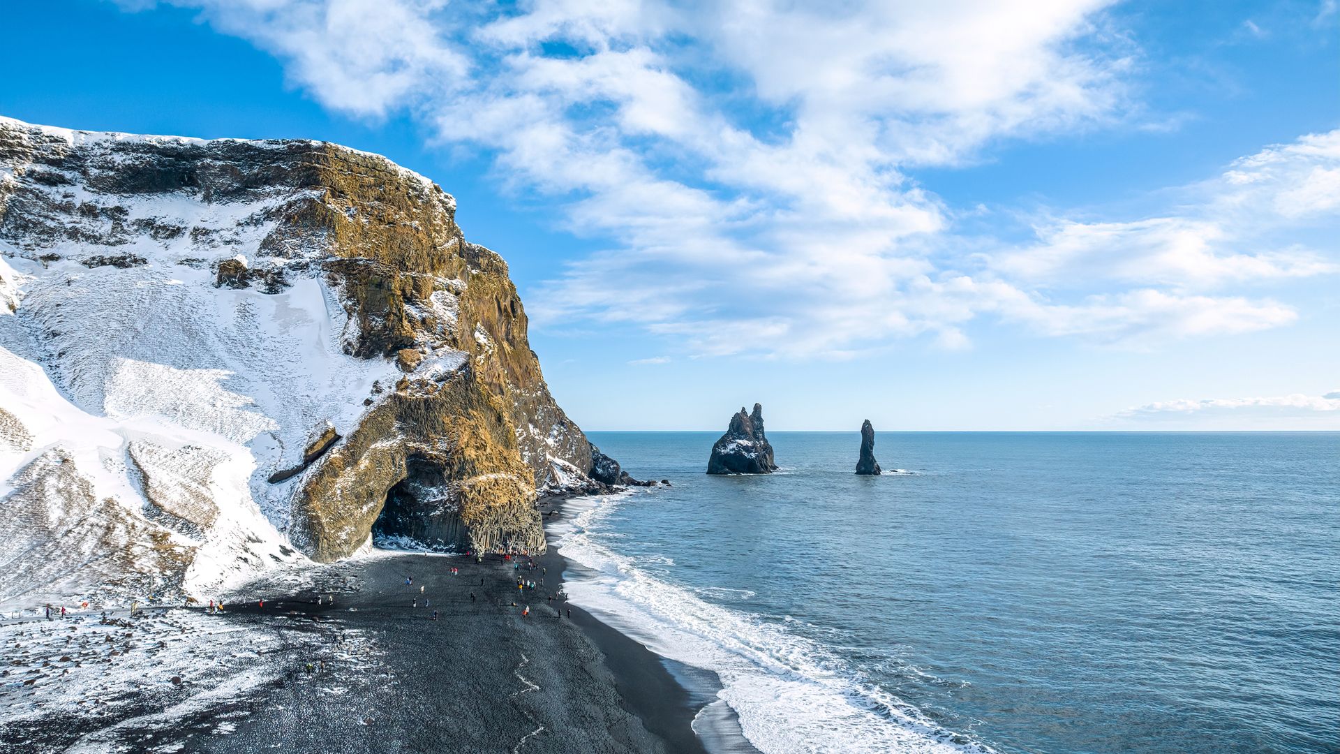 Aerial view of the black volcanic beach in Iceland and troll toes rocks in the sea. Vik