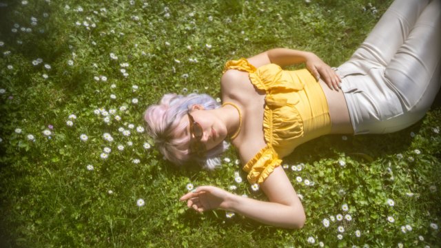 Young girl with coloured hair lies on the daisy blooming grass