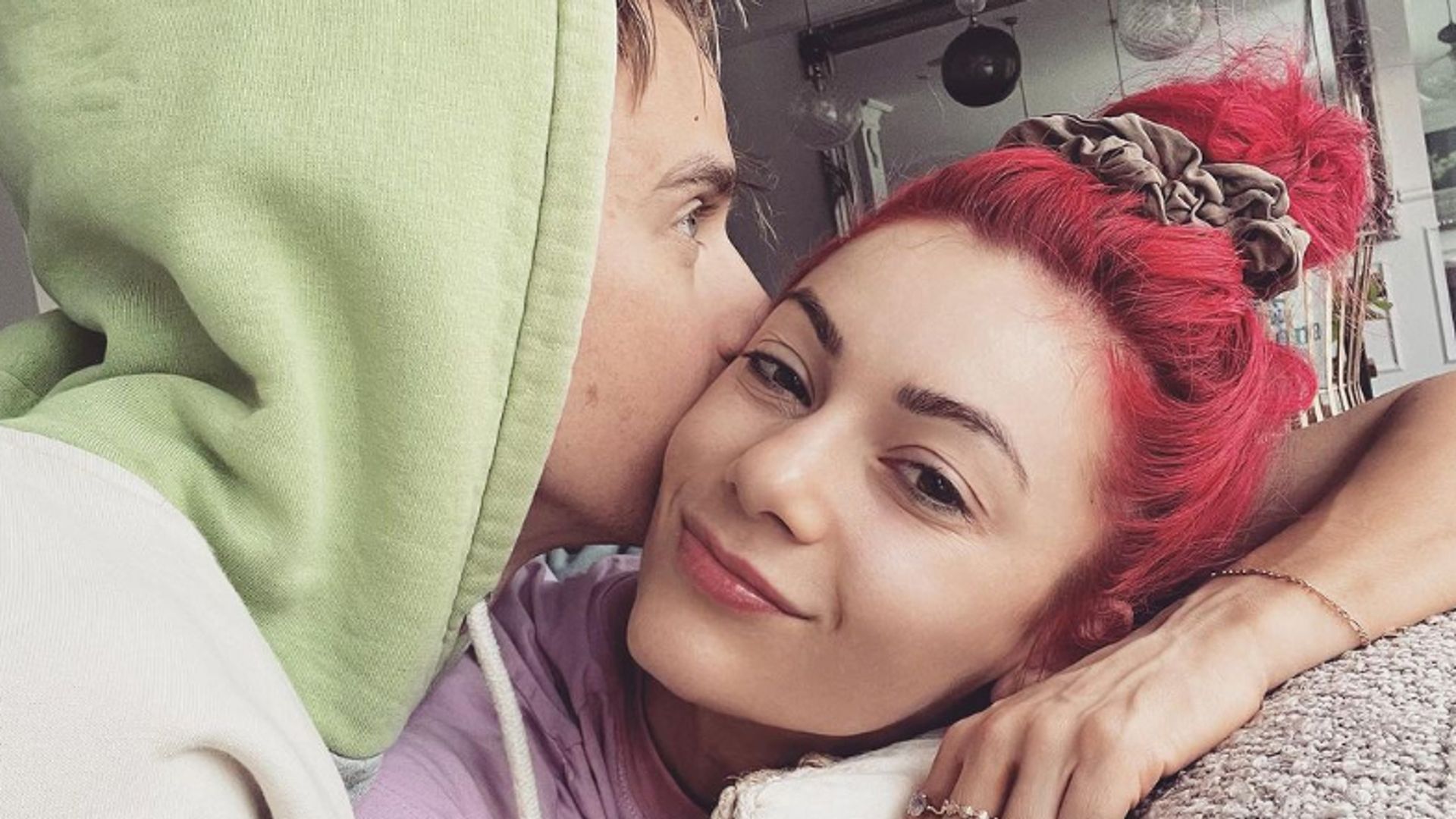 Joe Sugg in a green hoodie kissing Dianne Buswell on the cheek