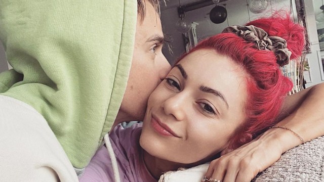 Joe Sugg in a green hoodie kissing Dianne Buswell on the cheek