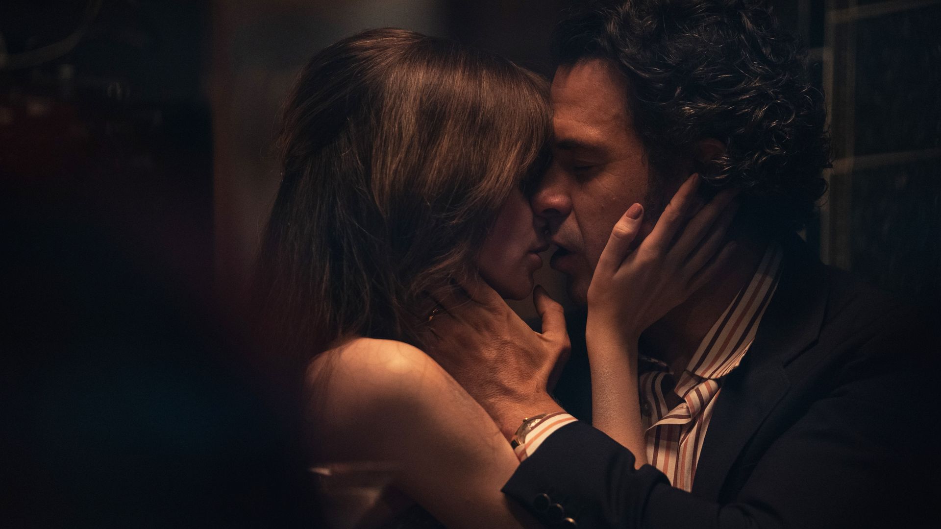 Man and woman kissing in dimly-lit room