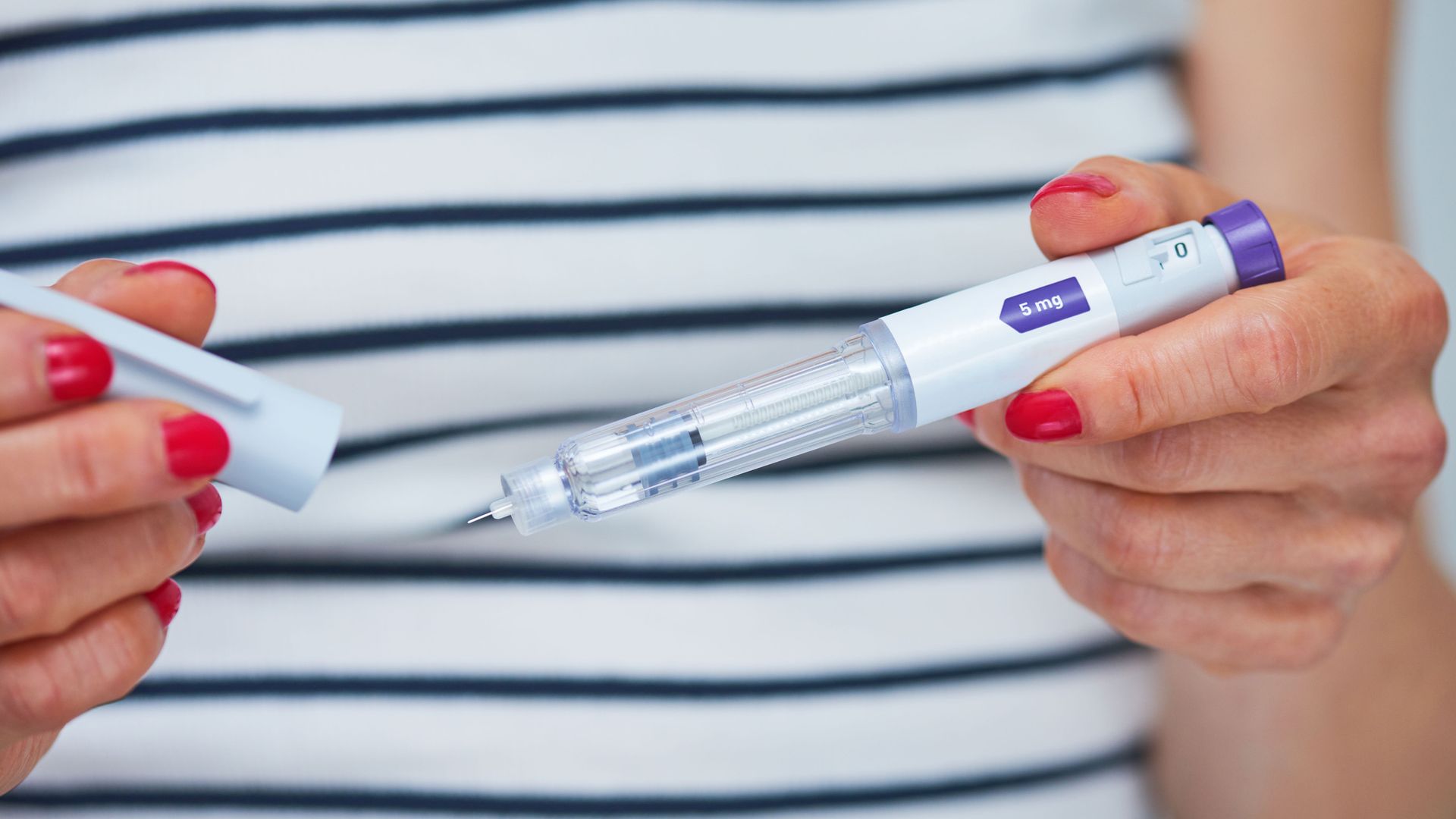 Woman using injection pen to administer weight loss drug -